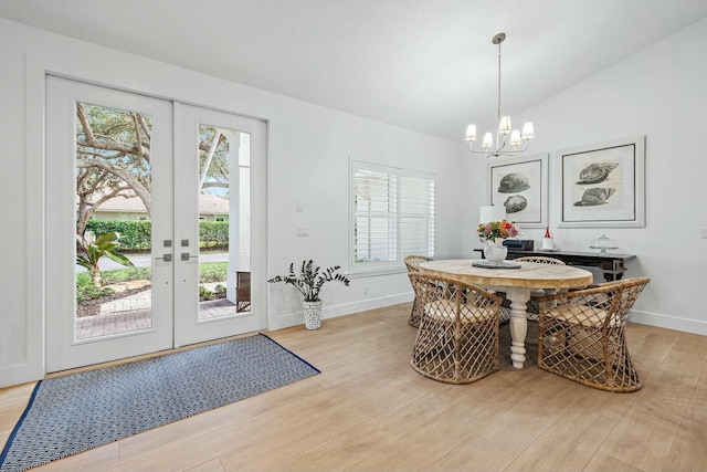 dining space featuring french doors, a healthy amount of sunlight, lofted ceiling, and light wood-type flooring