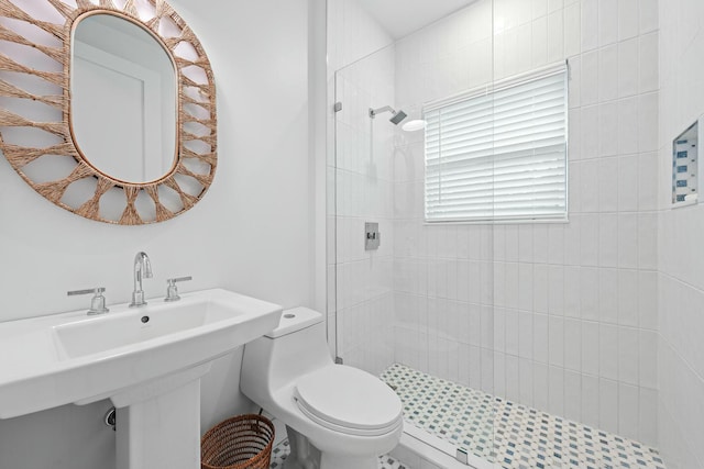 bathroom with a tile shower and toilet