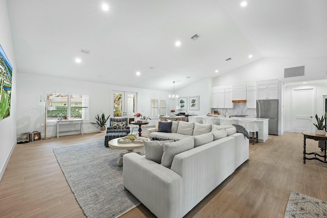 living room featuring light hardwood / wood-style flooring, a chandelier, and lofted ceiling