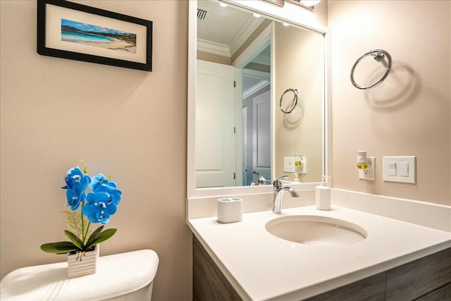 bathroom with vanity, toilet, and crown molding