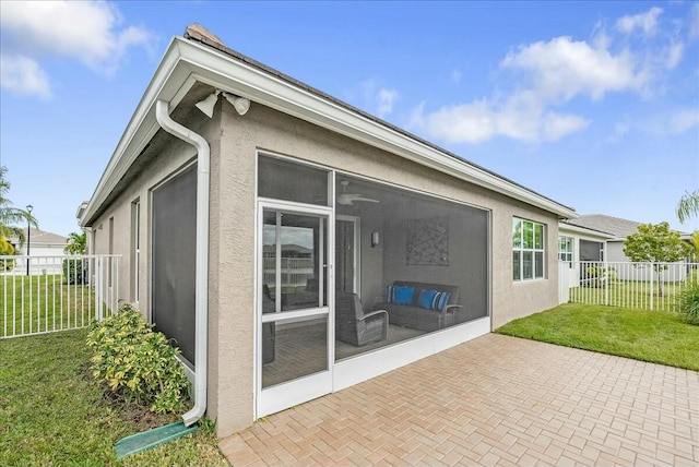 back of property with a lawn, a patio area, and a sunroom