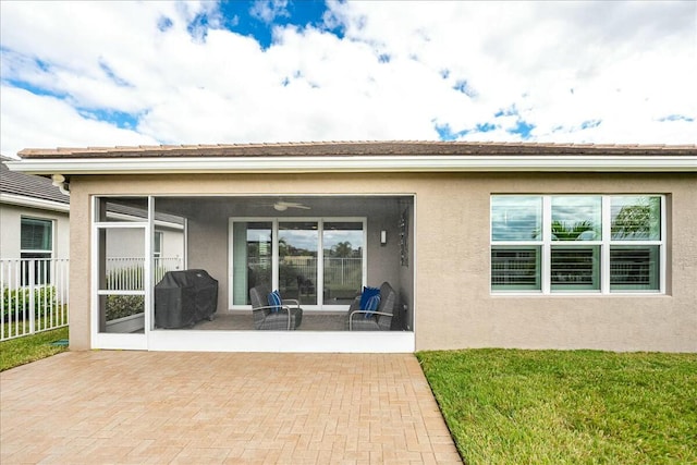 rear view of property with a sunroom, a yard, and a patio