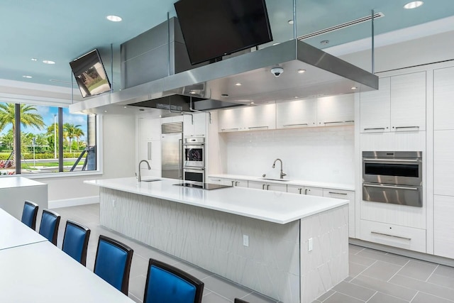 kitchen with pendant lighting, a breakfast bar, an island with sink, and stainless steel appliances