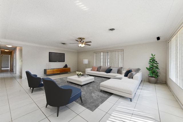 living room featuring ceiling fan, a textured ceiling, light tile patterned floors, and crown molding