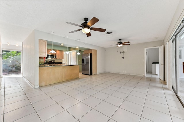 kitchen with appliances with stainless steel finishes, tasteful backsplash, pendant lighting, light brown cabinets, and light tile patterned flooring