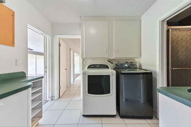 laundry room with light tile patterned flooring, cabinets, a textured ceiling, and washer and dryer