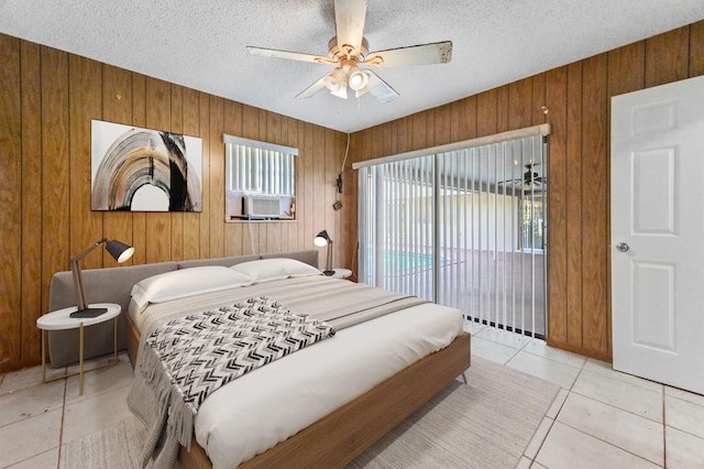 tiled bedroom with ceiling fan, access to outside, a textured ceiling, wood walls, and cooling unit