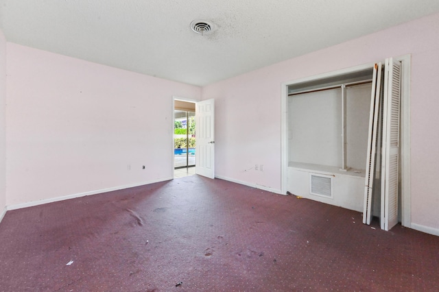 unfurnished bedroom featuring a textured ceiling, a closet, and dark carpet