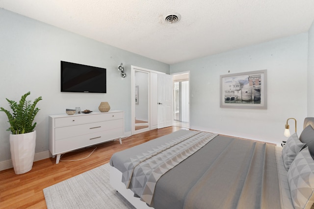 bedroom featuring light hardwood / wood-style floors, a textured ceiling, and a closet