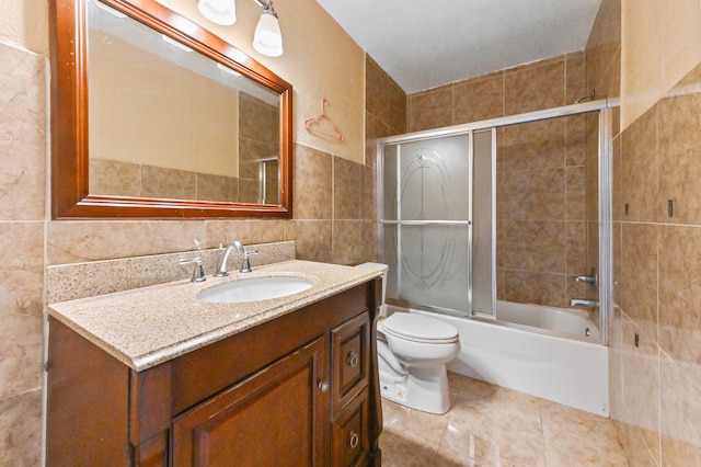 full bathroom featuring tile walls, combined bath / shower with glass door, vanity, and toilet