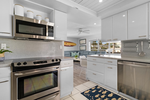 kitchen with white cabinets, ceiling fan, appliances with stainless steel finishes, and light hardwood / wood-style flooring