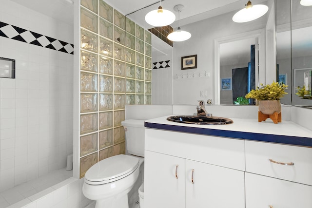 bathroom with a tile shower, vanity, and toilet