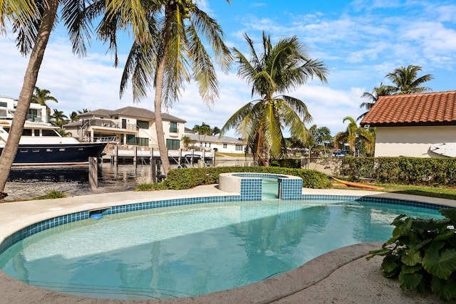 view of swimming pool with an in ground hot tub and a water view