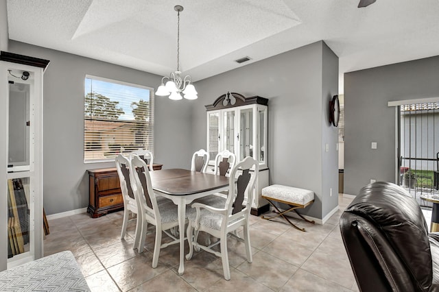 tiled dining room featuring a textured ceiling and an inviting chandelier