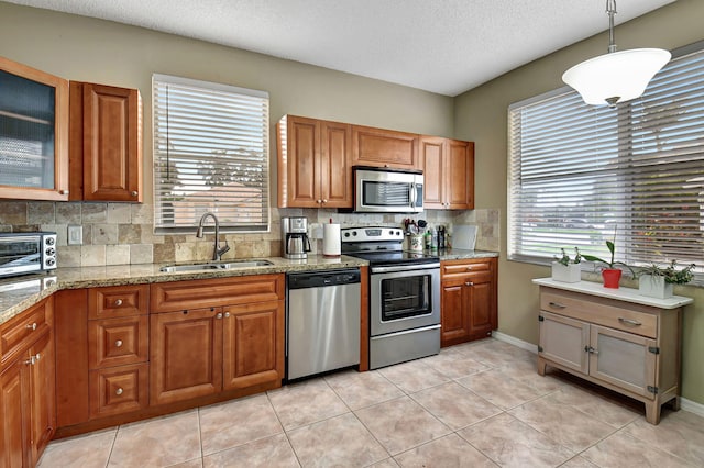 kitchen featuring decorative light fixtures, stainless steel appliances, plenty of natural light, and sink