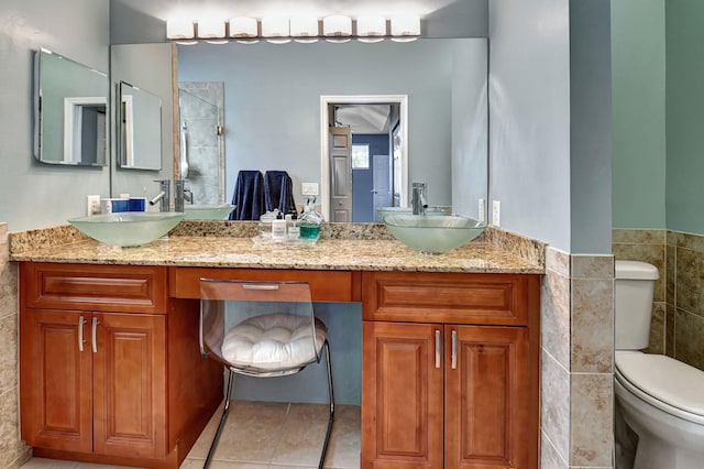 bathroom with tile patterned flooring, vanity, toilet, and tile walls