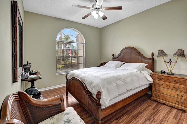 bedroom featuring ceiling fan, dark hardwood / wood-style flooring, and a textured ceiling