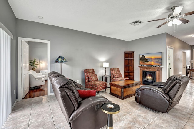 living room featuring ceiling fan, light tile patterned floors, and a textured ceiling