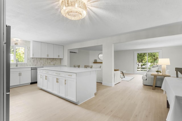 kitchen with white cabinetry, a chandelier, stainless steel dishwasher, a kitchen island, and light hardwood / wood-style floors