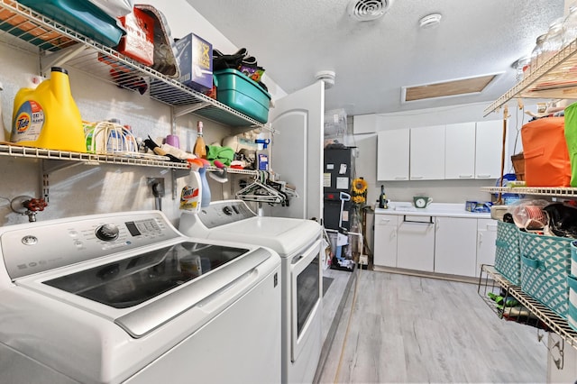 laundry area featuring a textured ceiling, washer and dryer, and light wood-type flooring