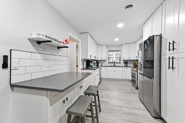 kitchen featuring sink, a breakfast bar area, white cabinetry, stainless steel appliances, and kitchen peninsula