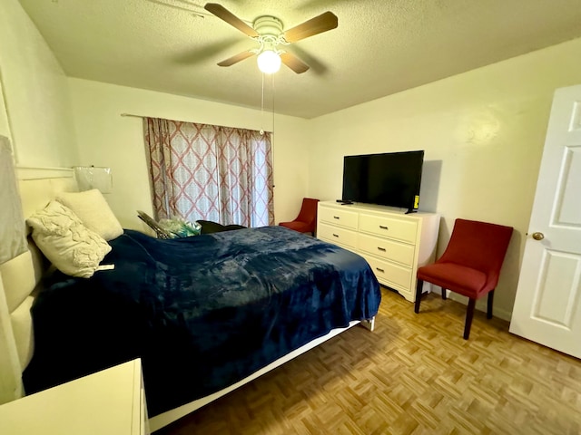 bedroom with ceiling fan, light parquet flooring, and a textured ceiling