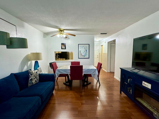 living room featuring a textured ceiling, ceiling fan, and dark hardwood / wood-style floors