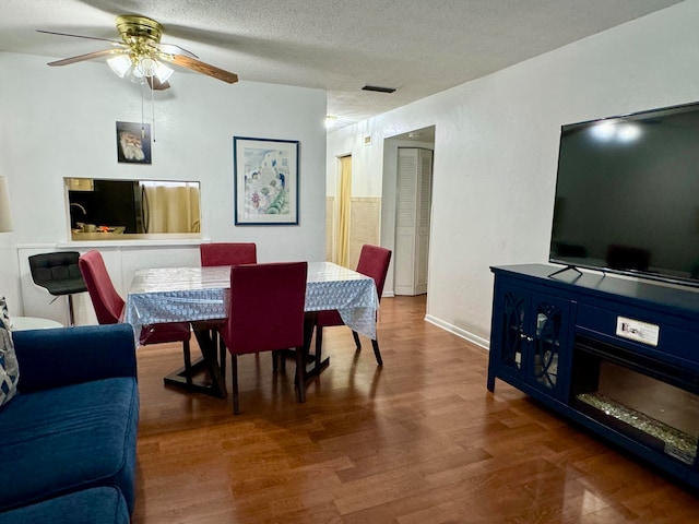 dining area featuring ceiling fan, dark hardwood / wood-style flooring, and a textured ceiling