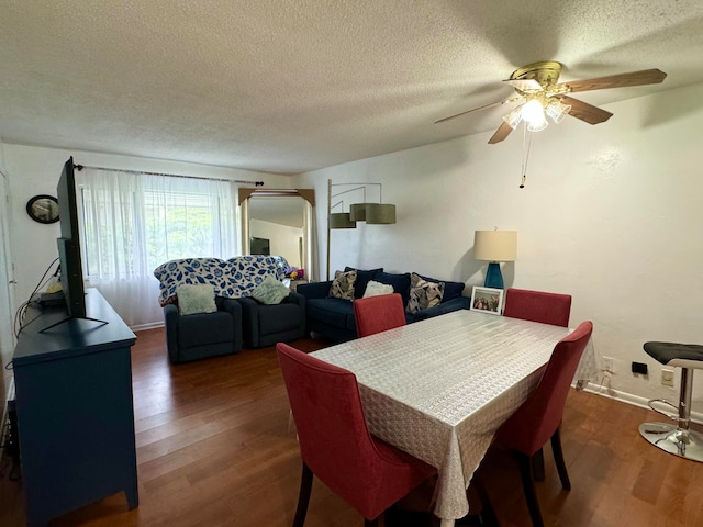 dining space with a textured ceiling, ceiling fan, and dark wood-type flooring