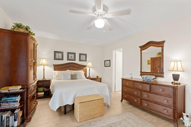 bedroom with ceiling fan, light hardwood / wood-style flooring, and a textured ceiling