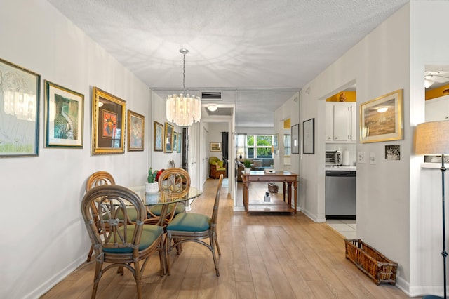 dining area featuring ceiling fan with notable chandelier, a textured ceiling, and light hardwood / wood-style flooring