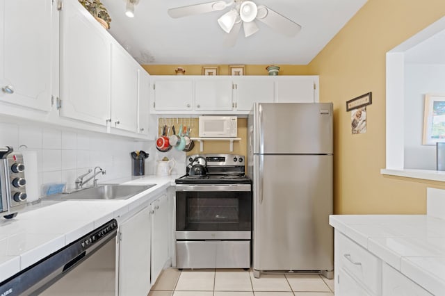 kitchen featuring tile counters, white cabinets, stainless steel appliances, and sink