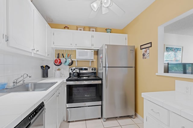 kitchen with tile countertops, white cabinetry, sink, and stainless steel appliances