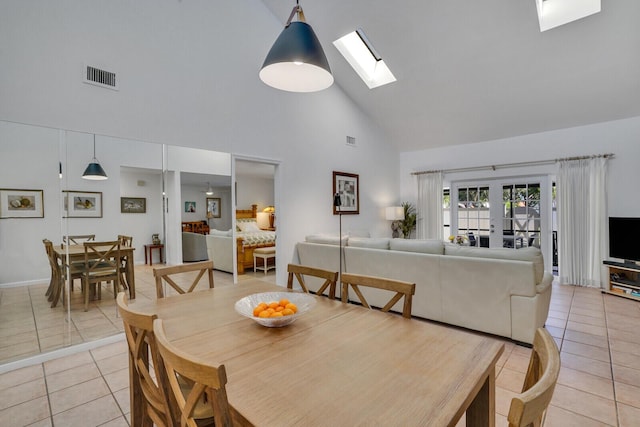 tiled dining room featuring a skylight, french doors, and high vaulted ceiling