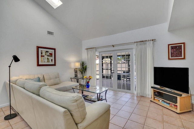 tiled living room with a skylight, french doors, and high vaulted ceiling