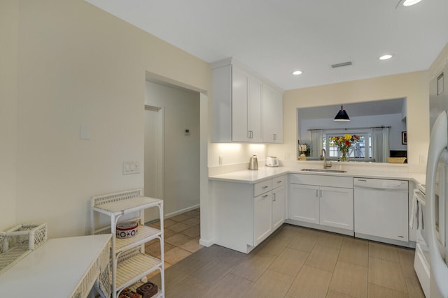 kitchen with white dishwasher, sink, light tile patterned floors, white cabinetry, and hanging light fixtures