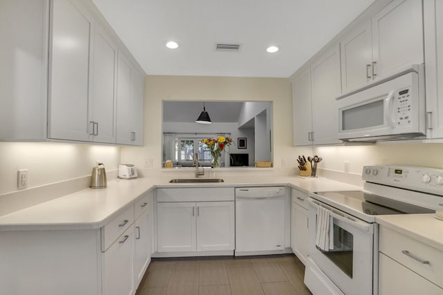 kitchen featuring white cabinetry, sink, decorative light fixtures, and white appliances