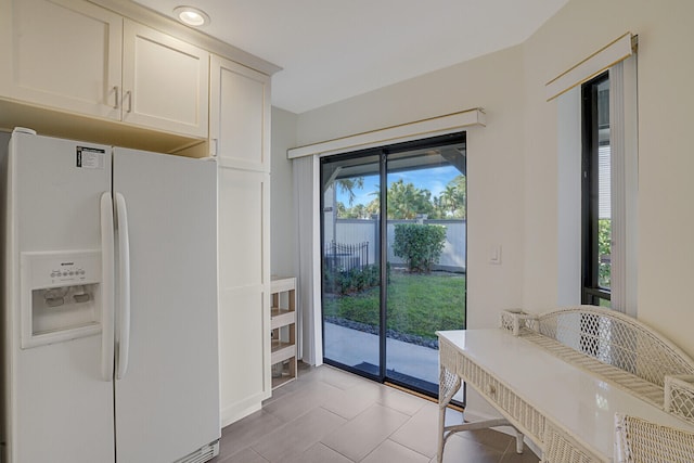 kitchen featuring light tile patterned floors, white cabinets, and white refrigerator with ice dispenser