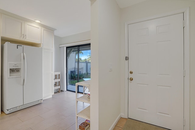 interior space featuring white cabinetry and white fridge with ice dispenser