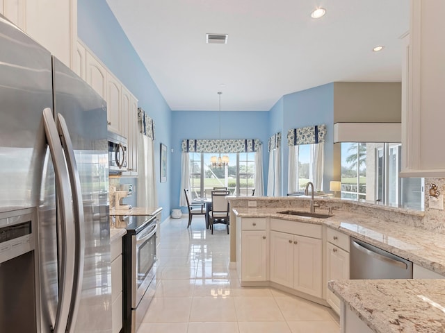 kitchen with appliances with stainless steel finishes, a wealth of natural light, hanging light fixtures, and sink