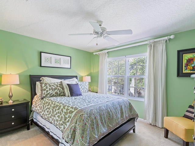 bedroom with a textured ceiling, light colored carpet, and ceiling fan