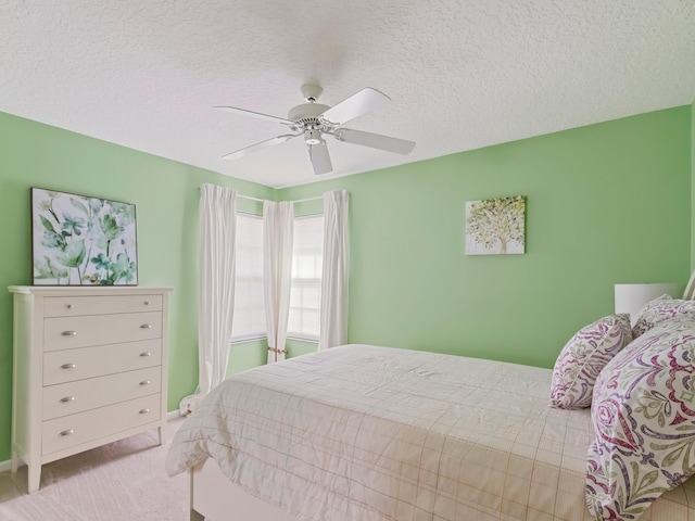 bedroom featuring a textured ceiling, light colored carpet, and ceiling fan