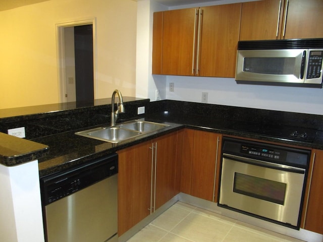 kitchen featuring kitchen peninsula, appliances with stainless steel finishes, sink, light tile patterned floors, and dark stone countertops