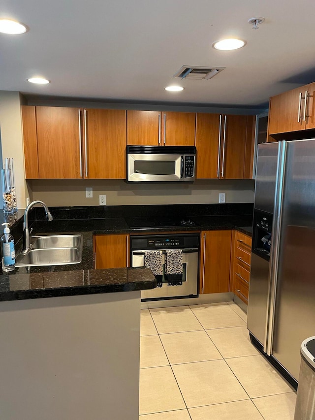 kitchen with sink, light tile patterned floors, dark stone counters, and appliances with stainless steel finishes