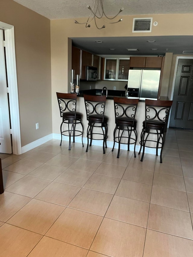 kitchen featuring sink, a textured ceiling, appliances with stainless steel finishes, kitchen peninsula, and a breakfast bar area