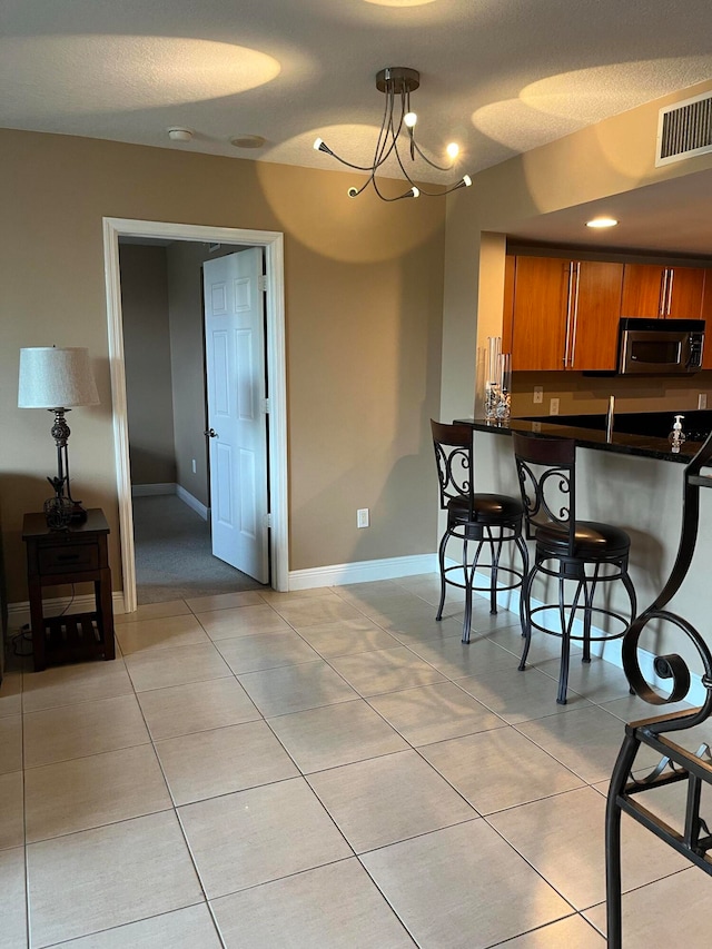 kitchen with a kitchen breakfast bar, kitchen peninsula, light tile patterned floors, and a textured ceiling