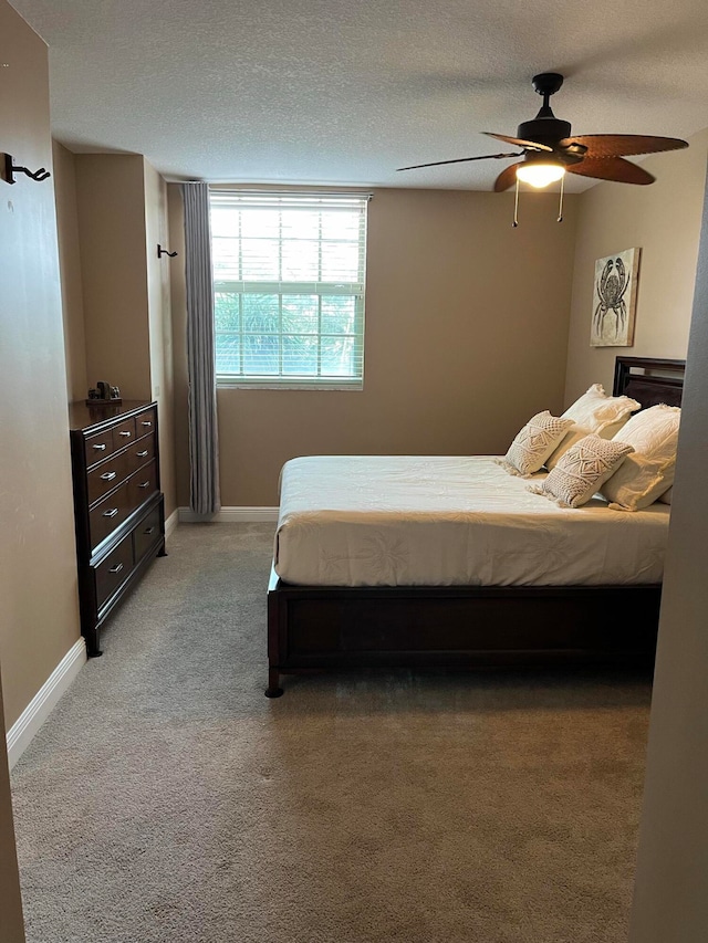 carpeted bedroom with ceiling fan and a textured ceiling