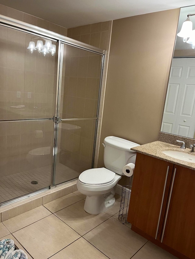 bathroom featuring toilet, vanity, tile patterned floors, and walk in shower