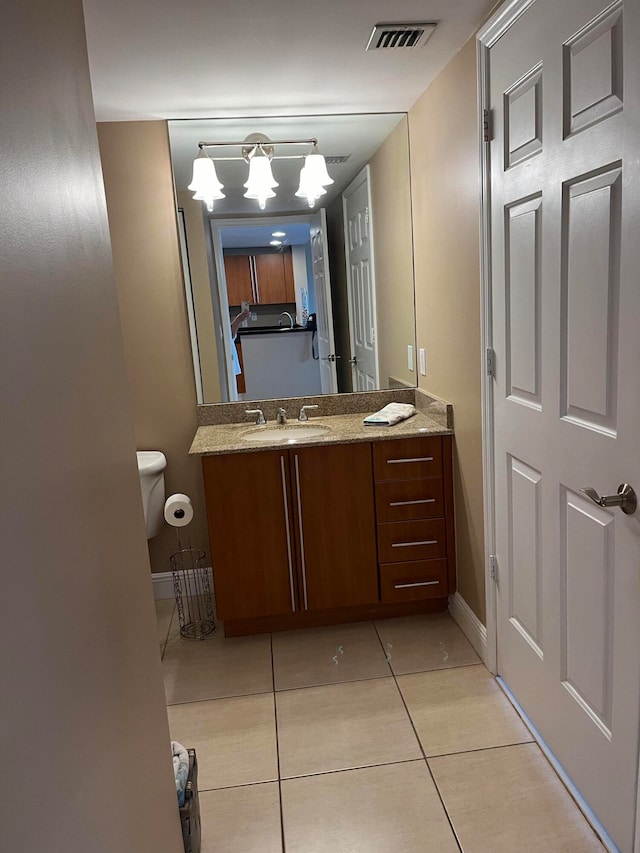 bathroom with tile patterned flooring, vanity, toilet, and a notable chandelier