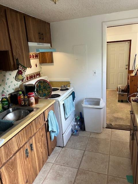 kitchen with white range with electric stovetop, sink, light tile patterned floors, and a textured ceiling